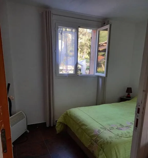 Chambre avec lit double et fenêtre ouverte sur la végétation