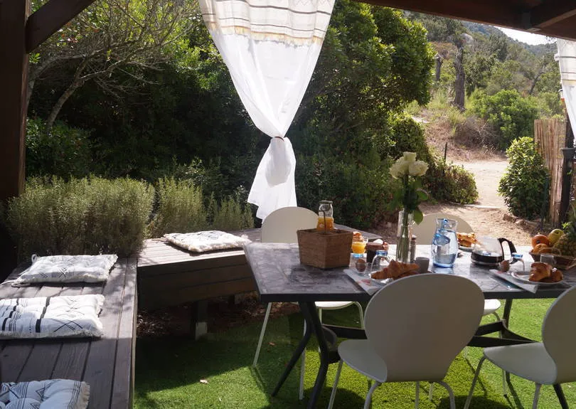 La terrasse ouverte sur le jardin et le maquis, banquette en bois et coussins